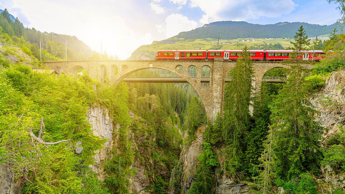 Roter Zug bei der Überquerung des Solis-Viadukts der Schweizer Eisenbahn in der Schweiz