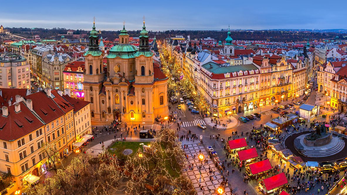Panoramablick von oben auf die Prager Skyline, die beleuchteten Gebäude und den traditionellen Weihnachtsmarkt