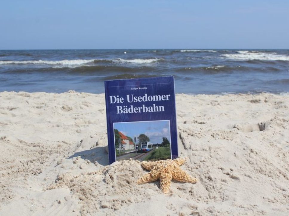 Buch "Die Usedomer Bäderbahn" steht im Sand am Meer