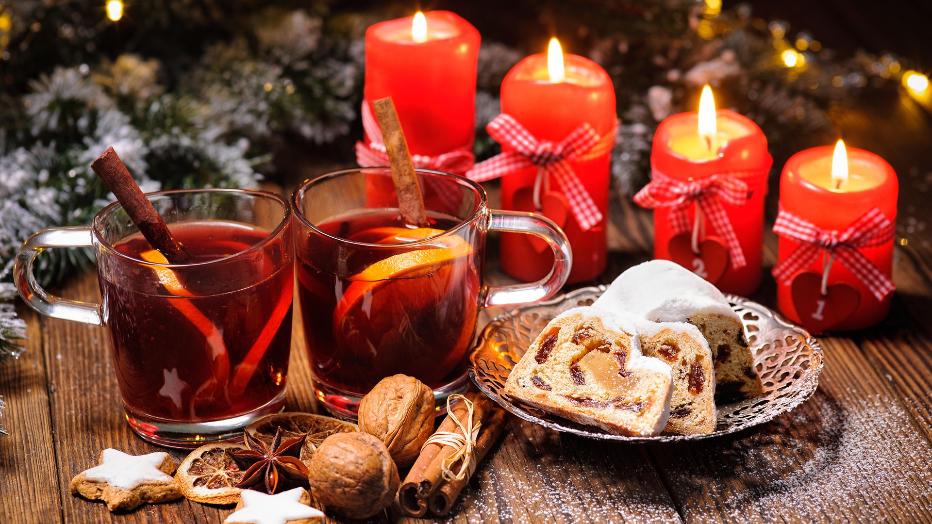 Weihnachtsglühwein auf einem Tisch mit brennenden Adventskerzen und Weihnachtsdekoration