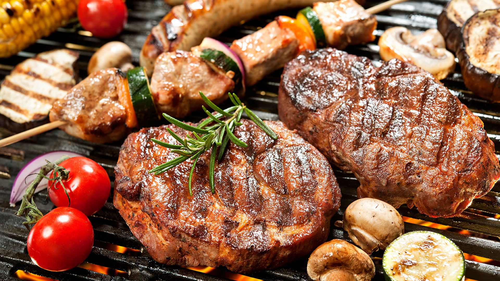 Köstlich gegrilltes Fleisch mit Gemüse über den Kohlen auf einem Grill